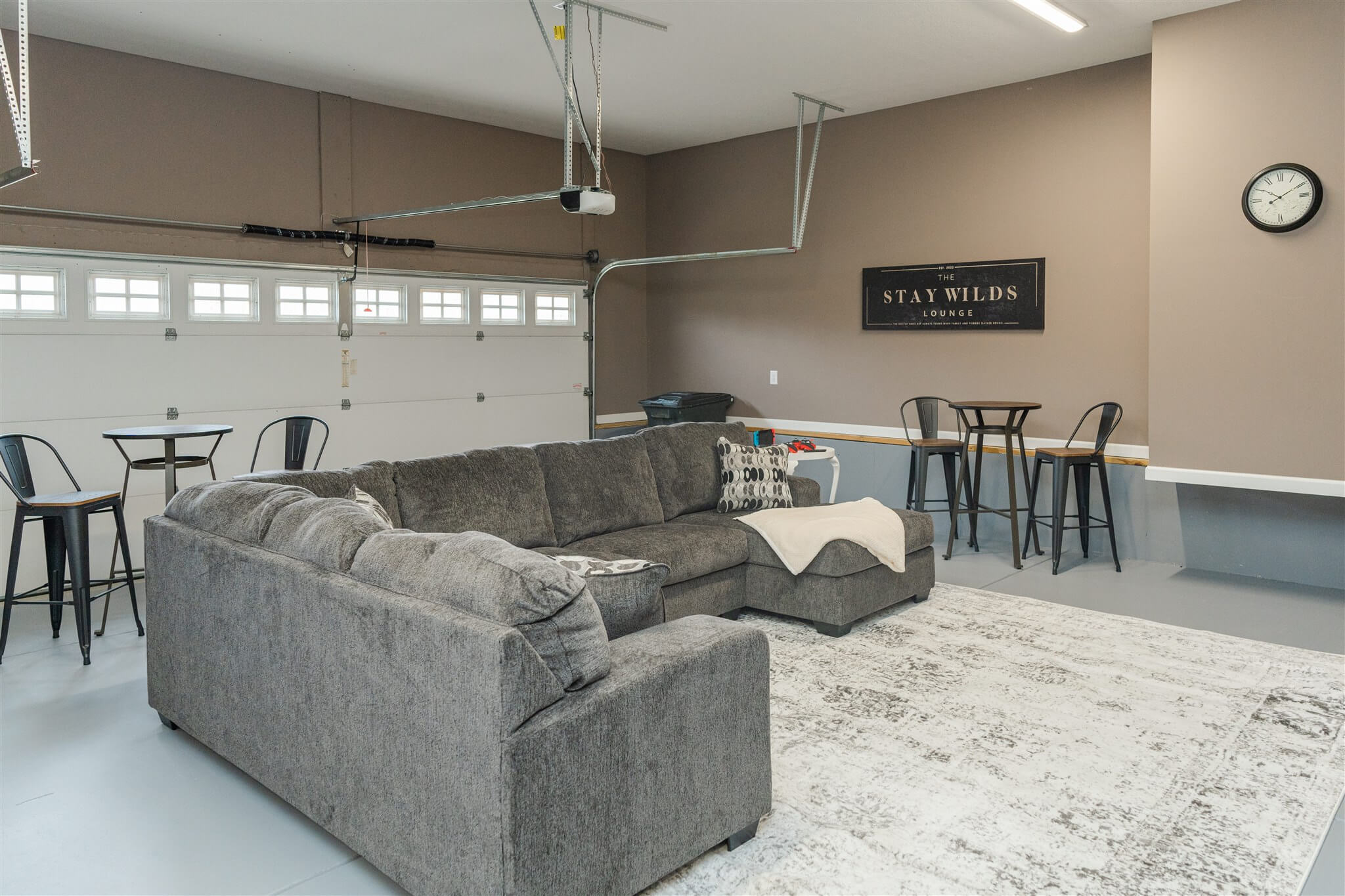 Garage lounge with sectional sofa and high-top tables